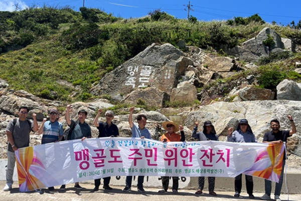 맹골도해상풍력발전 관계자들이 현수막을 들고 기념사진을 촬영하기 위해 포즈를 취하고 있다. [사진=맹골도해상풍력발전]