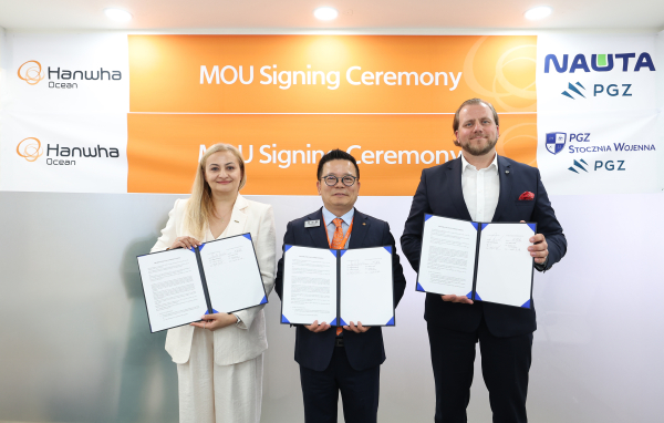 마덱스 전시회 부스에서 (왼쪽부터)모니카 코자키에비치 나우타 조선소 사장, 어성철 한화오션 특수선사업부장 사장, 마르친 링벨스키 PGZ SW 사장이 함정 건조 협력을 위한 양해각서를 체결하고 협약서를 들어 보이고 있다./사진=한화오션