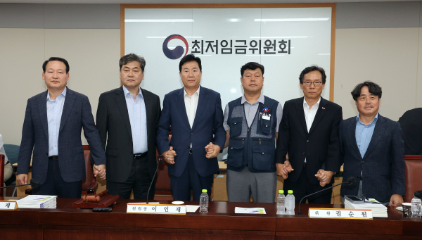 이인재 최저임금위원장(왼쪽 두 번째)이 10일 정부세종청사에서 열린 제12차 전원회의에서 내년 최저임금을 시간당 1만320원으로 17년만에 합의로 결정한 뒤 공익위원-사용자위원-근로자위원과 손을 잡고 있다./사진=연합뉴스