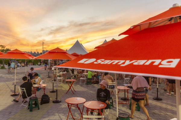 시민들이 삼양식품 파라솔 아래에서 라면을 맛보고 있다./사진=삼양식품