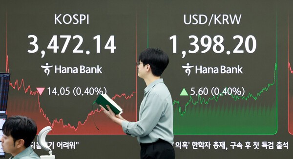 24일 서울 을지로 하나은행 본점 딜링룸에서 한 외환딜러가 증시 현황판 앞을 지나고 있다. / 사진 = 연합뉴스