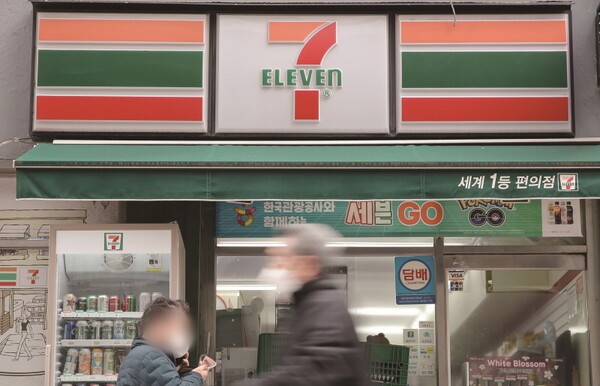 코리아세븐은 지난해에 이어 올해도 2년 연속 인력 감축에 나섰다. 서울의 한 세븐일레븐 매장 앞을 시민들이 지나치고 있다./사진=연합뉴스<br>