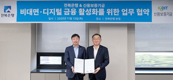 채병호 신용보증기금 이사(오른쪽)와 서두원 전북은행 부행장이 지난 13일 전북은행 본점에서 열린 ‘비대면·디지털 금융지원 활성화를 위한 업무협약’을 체결한 뒤 협약서를 들어 보이고 있다. / 사진 = 신용보증기금<br>